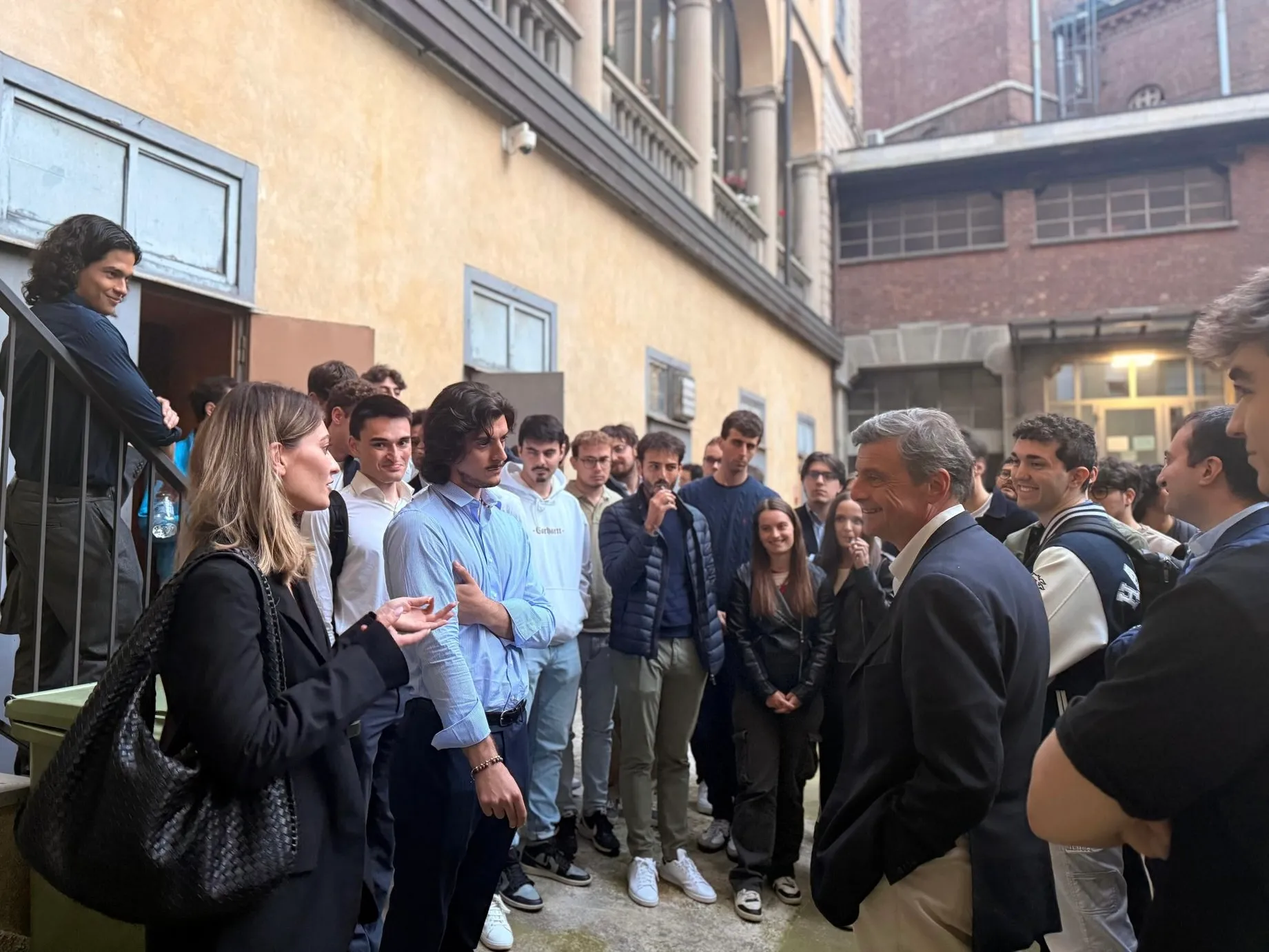 University students chatting with a guest speaker in the courtyard of Pensionato Bertoni