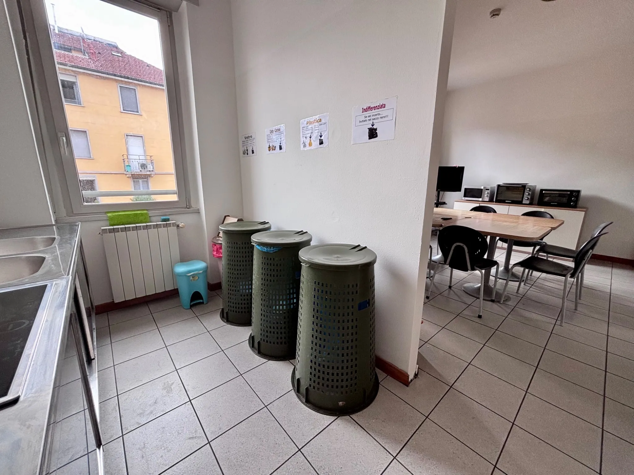 Cucina della residenza universitaria con cestini raccolta differenziata e area pranzo