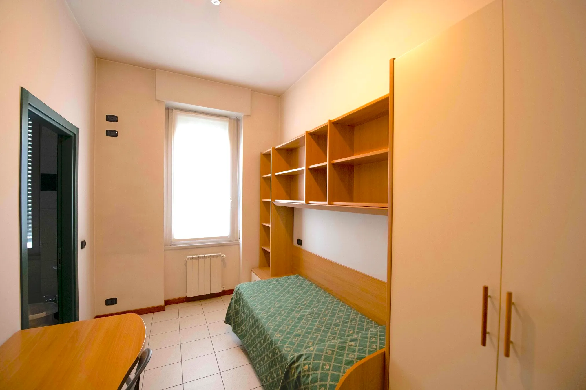 Camera singola arredata con letto e scrivania nella residenza universitaria