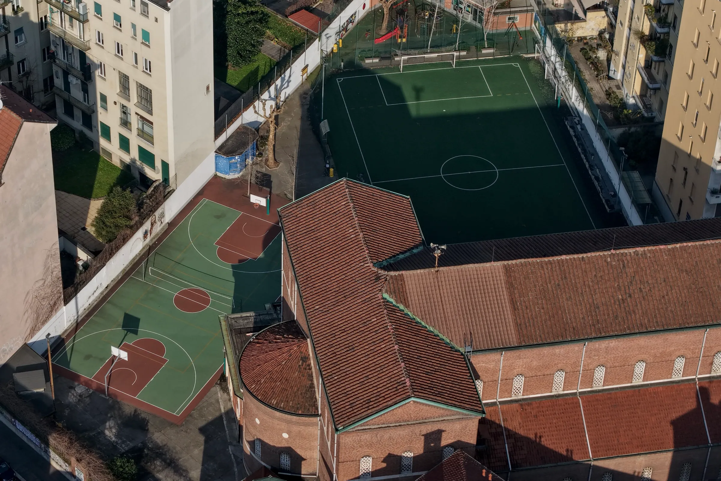 Campi sportivi della residenza universitaria con campo da basket, campo da calcio e la chiesa del complesso