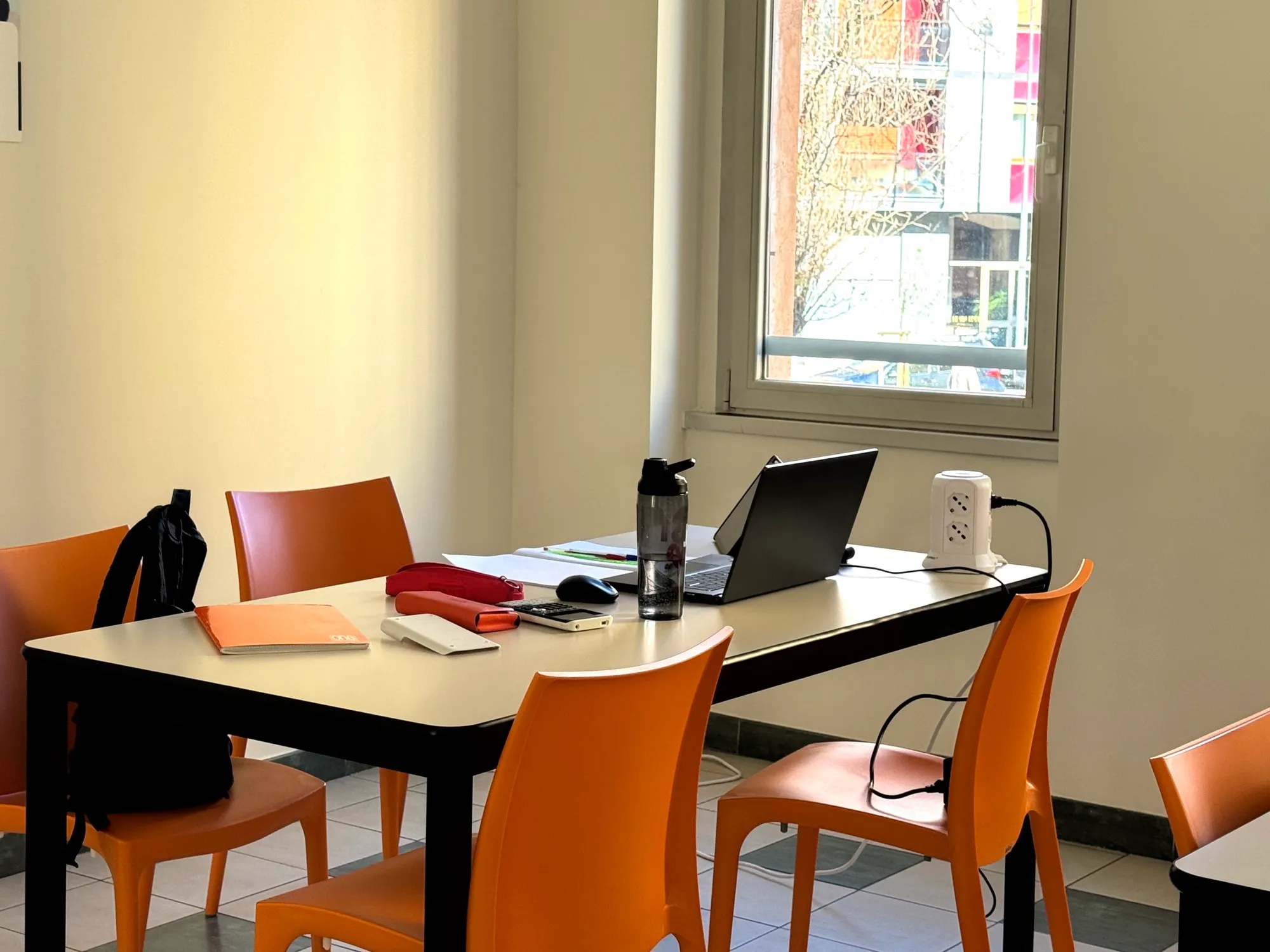 Sala studio della residenza universitaria con scrivania, laptop e ciabatta elettrica