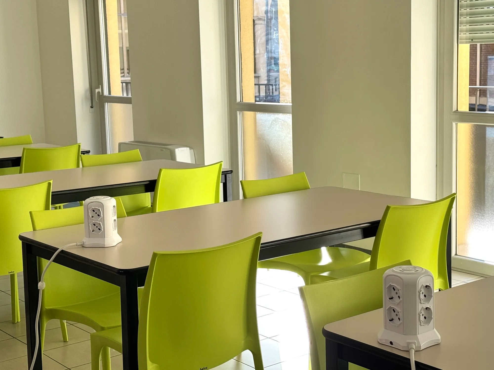 Sala studio della residenza studenti con luce naturale e sedie verdi